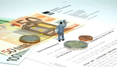 Erste Seite eines Rentenbescheides und darauf abgelegtes Bargeld