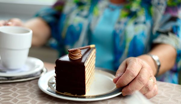 Seniorin mit einem Kaffee und einem Stück Torte